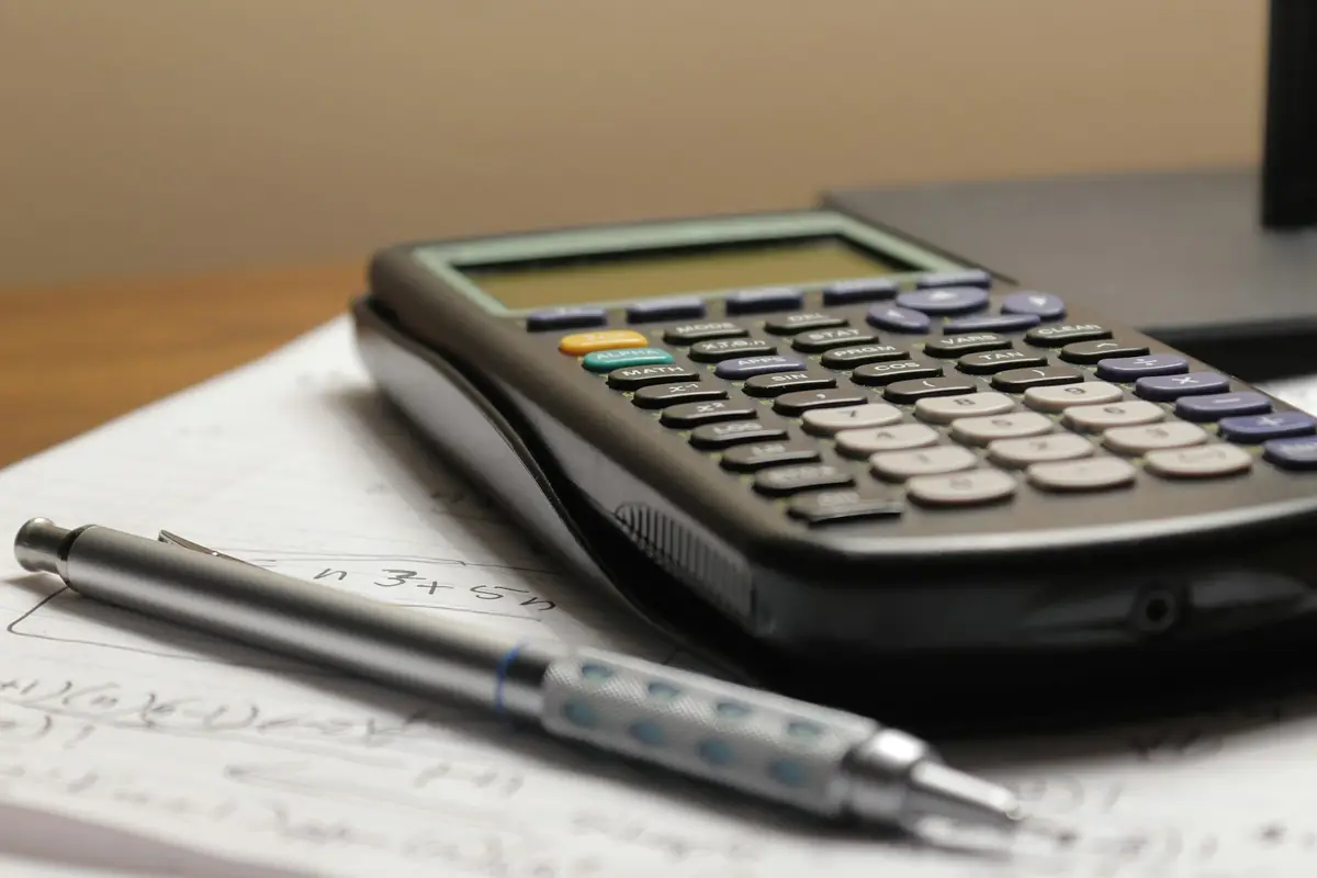 A calculator and pen resting on a printed bill